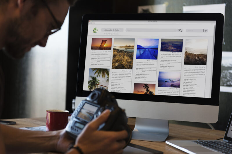A photographer looking at images in his camera, while also considering investing in websites.