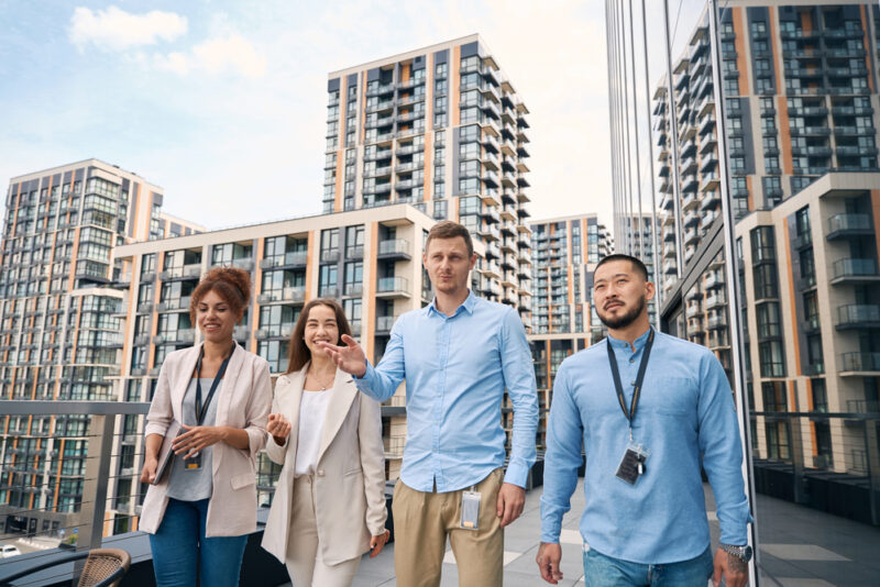 A group of people affiliate with a Real Estate Investment Trust (REIT) surveying their properties, which have been funded by investors seeking to diversify from traditional investments.