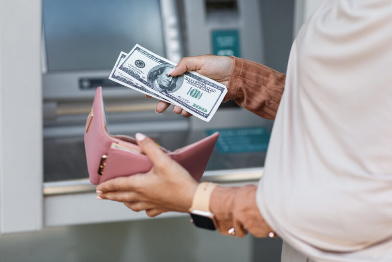 A woman withdrawing money from an ATM, thanks to her investing cash flow.